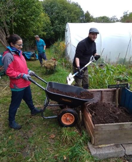 garden volunteers emptying wheel barrow