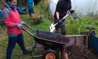 garden volunteers emptying wheel barrow