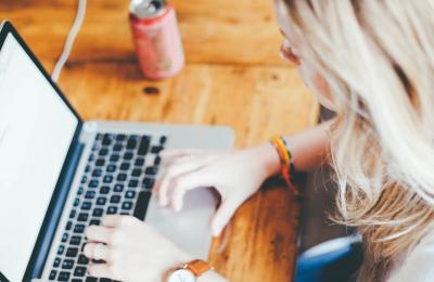 Female working on a Mac book on a wooden table