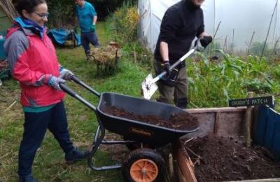 garden volunteers emptying wheel barrow